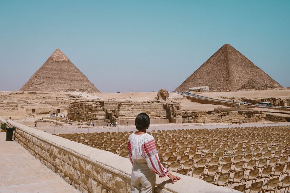 Afrika pro cestovatele | Kam jet poprvé, Historie a kultura 2 A tourist admires the Great Pyramids and Sphinx in Giza, Egypt under the clear daytime sky.