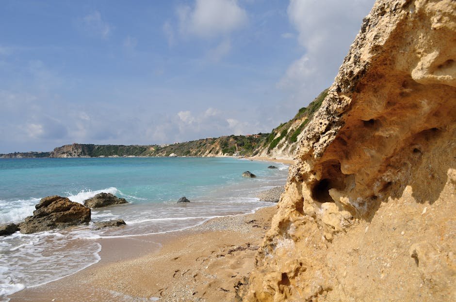 Kefalonia | Co dělat, TOP místa, která musíte vidět 2 Sunlit rocky shore of Avithos Beach in Greece with turquoise waters and clear sky.