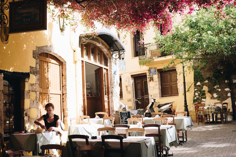 Kréta pro páry y rodiny | co dělat a vidět na dovolené 2 A quiet outdoor cafe in Chania, Greece, under sunlight and vibrant flowers.