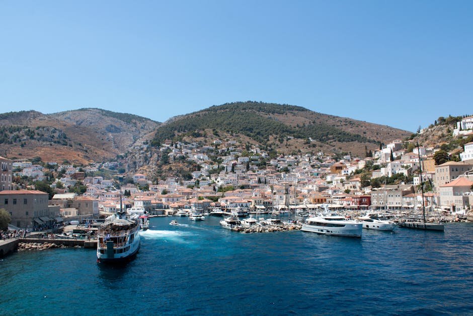 Co vidět na ostrově Hydra: Přístav, kláštery a výhledy 3 A vibrant view of Hydra Island's picturesque harbor with boats and buildings under a clear blue sky.