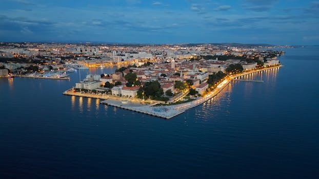 Stunning aerial view of Zadar's illuminated coast at twilight, showing the vibrant cityscape.