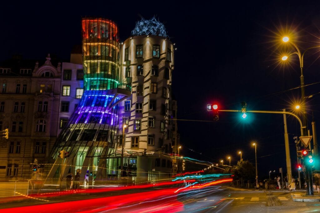 Long exposure night shot of Prague's illuminated Dancing House with light trails.