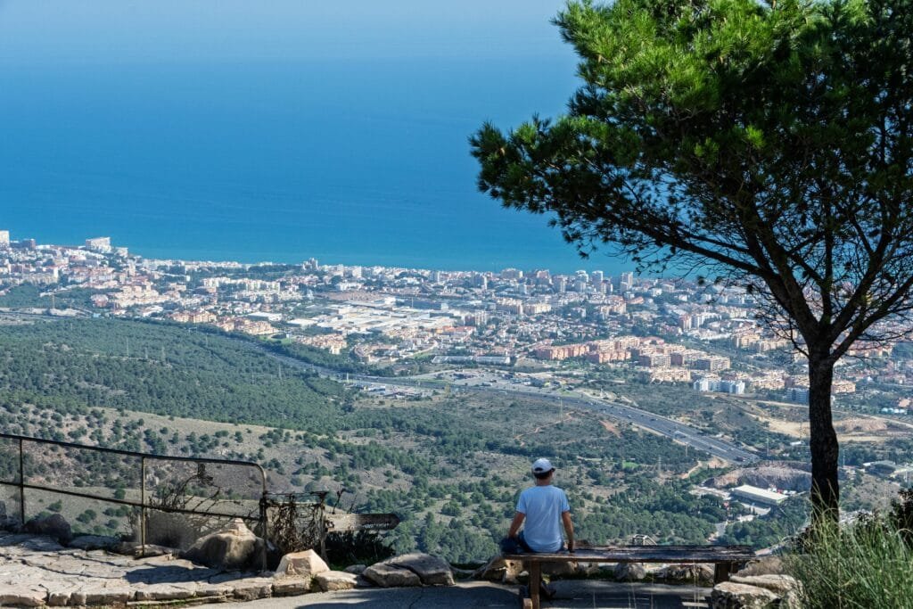Person enjoying panoramic view of Benalmádena and Mediterranean coastline from Mount Calamorro.