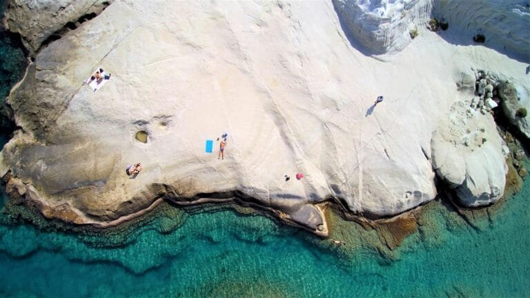 A breathtaking aerial view of Sarakiniko Beach in Milos, Greece, showcasing white rock formations and azure waters.