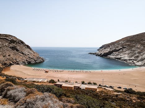 A stunning aerial view of a tranquil beach cove in Andros, Greece, with clear blue waters and sandy shores.