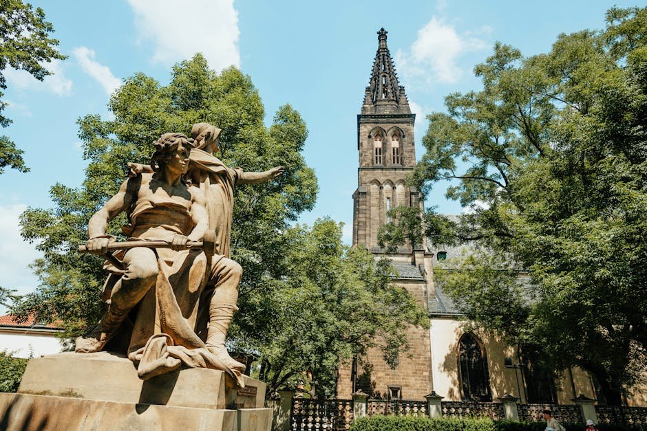A stunning view of Vysehrad's Gothic tower and historic statue surrounded by lush trees in Prague.
