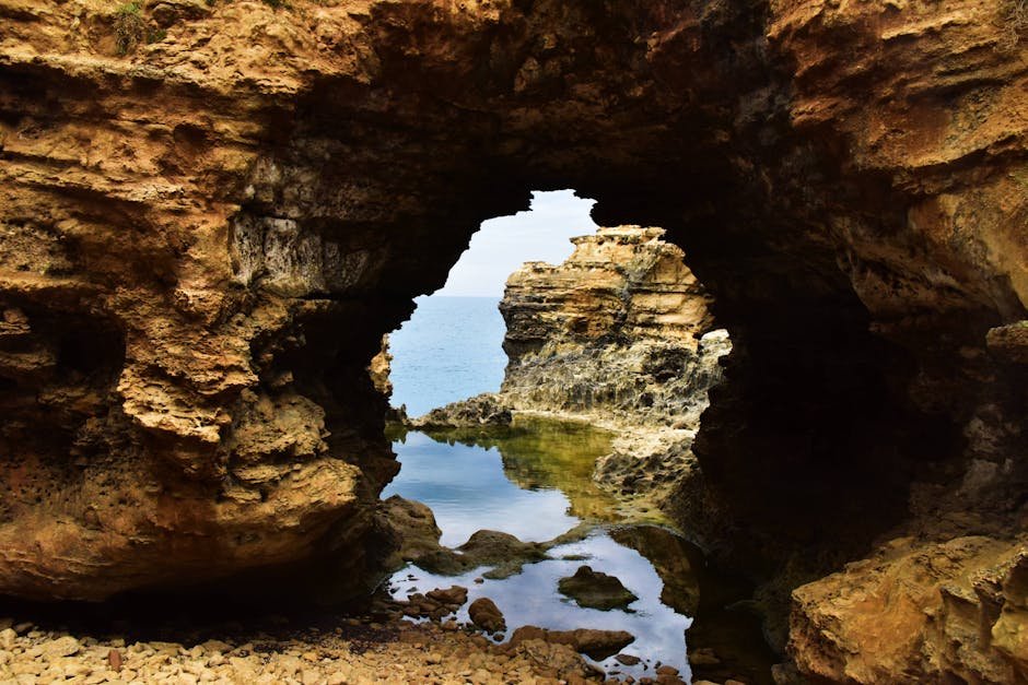 A breathtaking view through a natural archway, highlighting unique rock formations and the distant ocean.