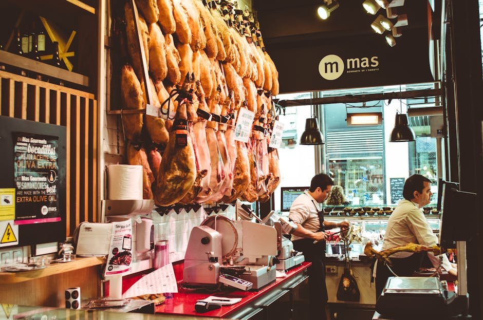 A bustling Spanish ham shop with hanging cured meats and two men serving customers.