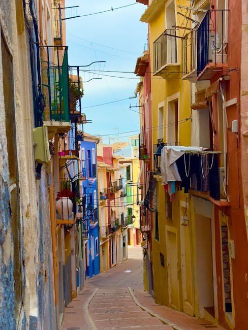 Narrow vibrant street in a historic Mediterranean town, showcasing colorful buildings.