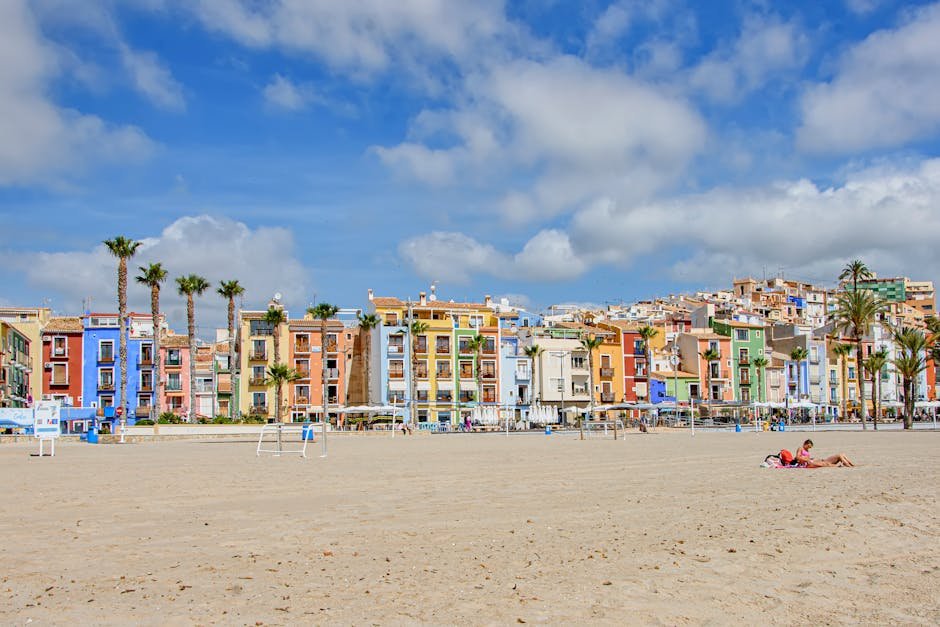 Charming view of colorful buildings lined up by the beach in Villajoyosa, Spain, under a bright sky.