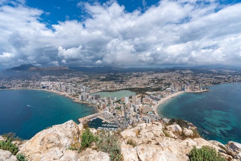 Stunning aerial photo of Calpe's skyline and shimmering coastline under a dramatic cloudy sky.