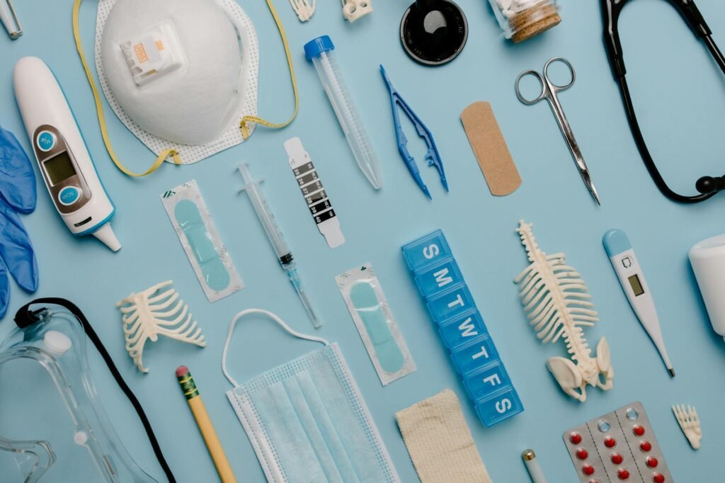 A comprehensive flat lay of diverse medical supplies including PPE and diagnostic equipment on a blue surface.