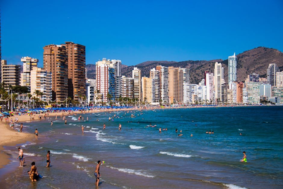 Beautiful beach scene with high-rise buildings in Benidorm, Spain under a clear blue sky.