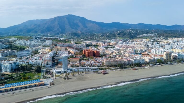 Stunning aerial view of Estepona's beachfront cityscape with mountains in the background.