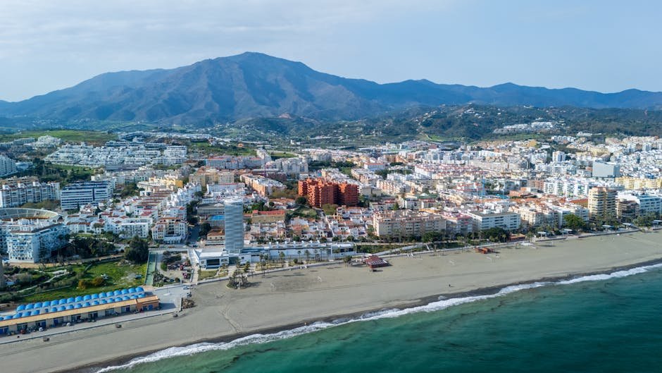 Stunning aerial view of Estepona's beachfront cityscape with mountains in the background.