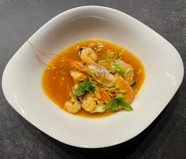 A vibrant seafood soup featuring fresh shrimps and fish in a rich broth.