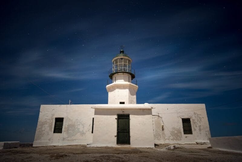 A stunning view of a lighthouse against a starry sky in Mikonos, Greece.