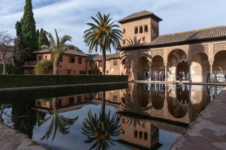 Stunning view of the Alhambra's intricate architecture reflected in a tranquil pond.
