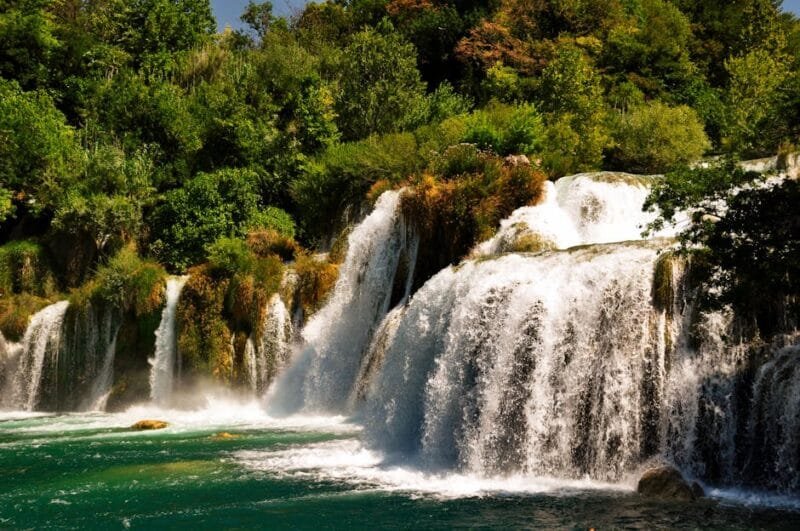 Parco Nazionale di Krka | Cascate Smeraldine della Croazia 1 Beautiful cascading waterfalls surrounded by lush greenery in a serene Croatian forest setting.
