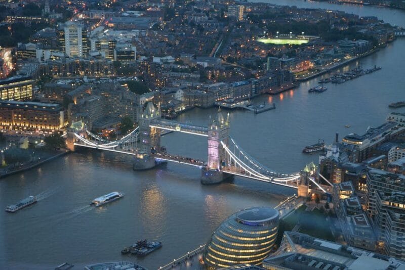 Londra | Top Destinazioni e Consigli di Viaggio 1 A stunning aerial photograph capturing London's Tower Bridge illuminated at night over the Thames River.