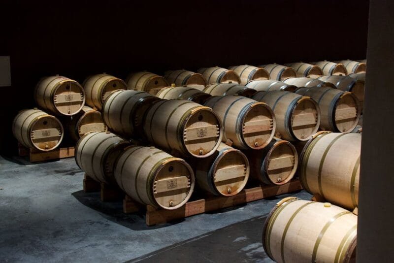 La France | Attrazioni principali e cosa fare il viaggio 3 Stacked oak wine barrels in a dimly lit cellar in Pauillac, France.