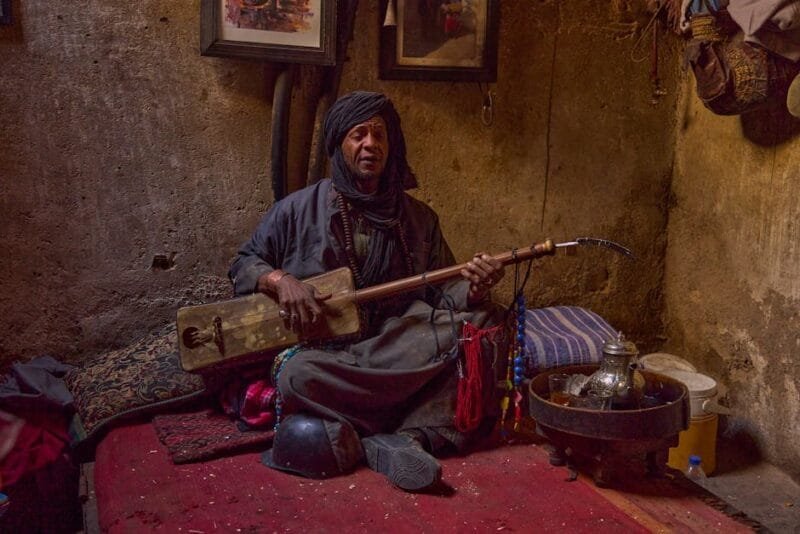 A Moroccan musician playing a traditional instrument inside a Marrakesh home.