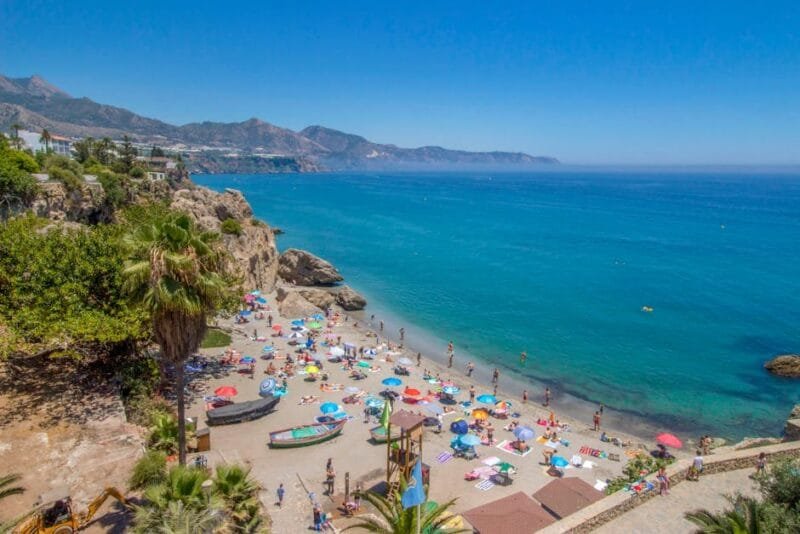 Colorful beach scene at Málaga with umbrellas and people enjoying the summer day.