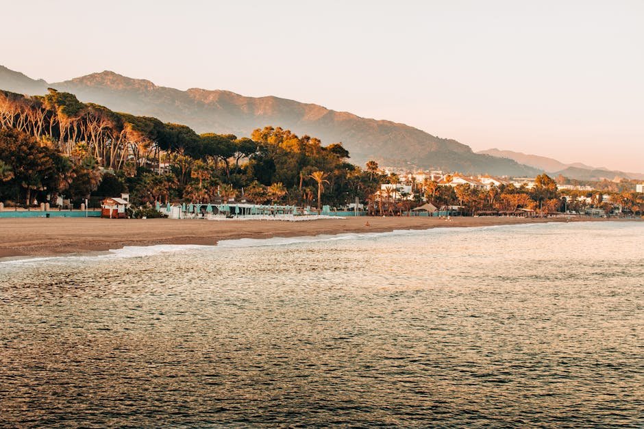 Marbella | Tipy Pre Elegantný a Nezábudný Pobyt v Marbelli 1 Pokojný výhľad na východ slnka na pláž Marbella s horami a sviežou zeleňou v Španielsku.
