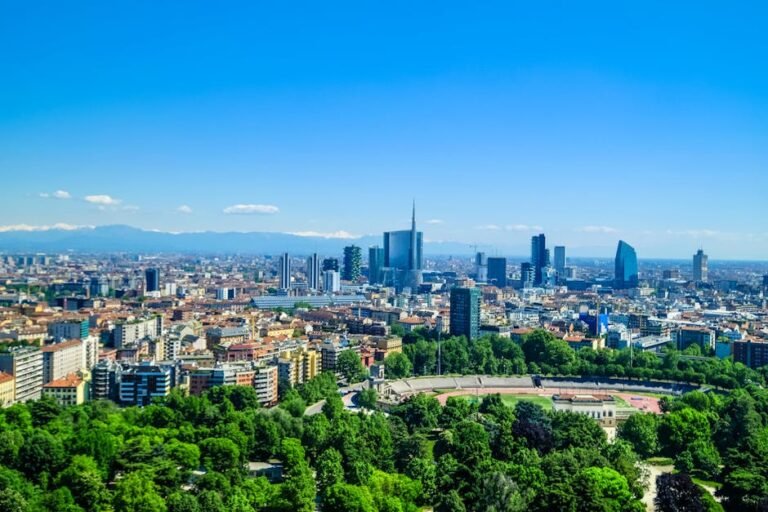 Lombardia | Čo vidieť v srdci severného Talianska 1 Panoramic view of Milan's skyline featuring modern skyscrapers and lush greenery under a clear blue sky.