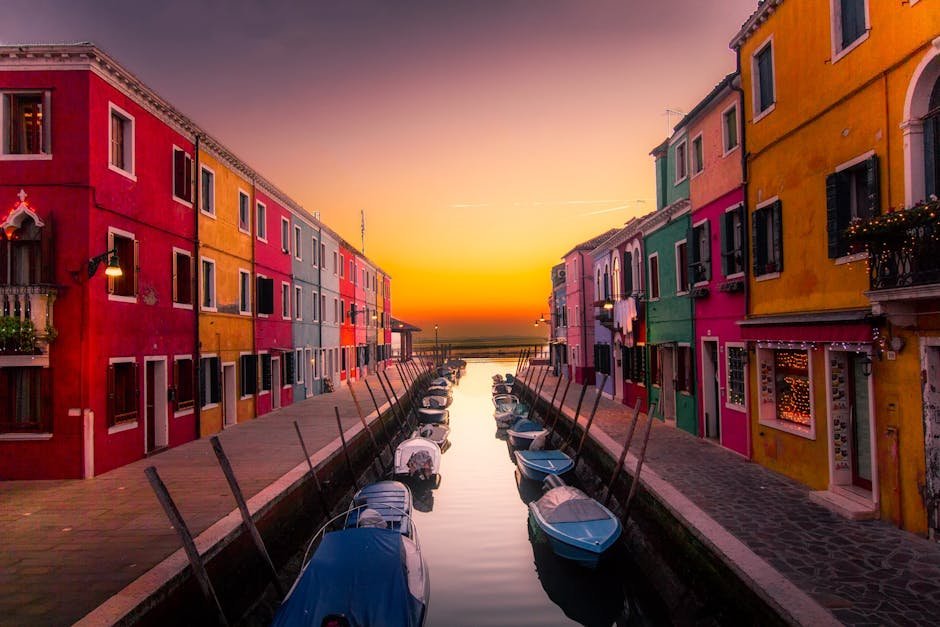 Dovolenka - Vibrant facades along Burano's canal with boats at serene sunset. Perfect travel snapshot.