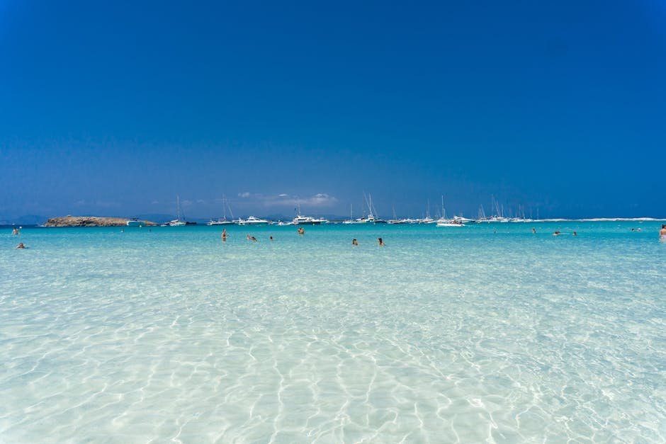 Ses Illetes – Formentera | Prírodný raj s bielym pieskom 2 Enjoy leisure time at a Spanish beach with turquoise waters and distant yachts, perfect for summer vacation.