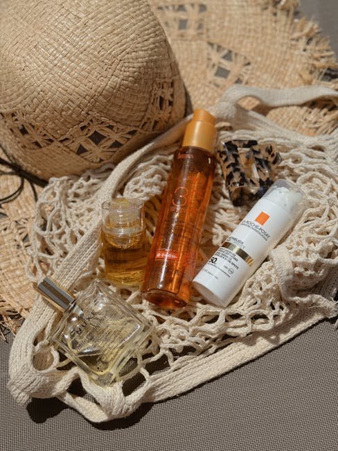 Stylish flat lay of beach bag essentials including a straw hat, sunscreen, and perfume for summer relaxation.